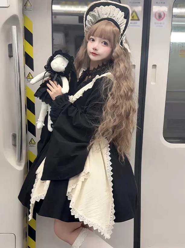 Side front angle of Gothic Lolita maid dress showing cream lace apron, bell sleeves, maid hair headdress, and complete ensemble styling