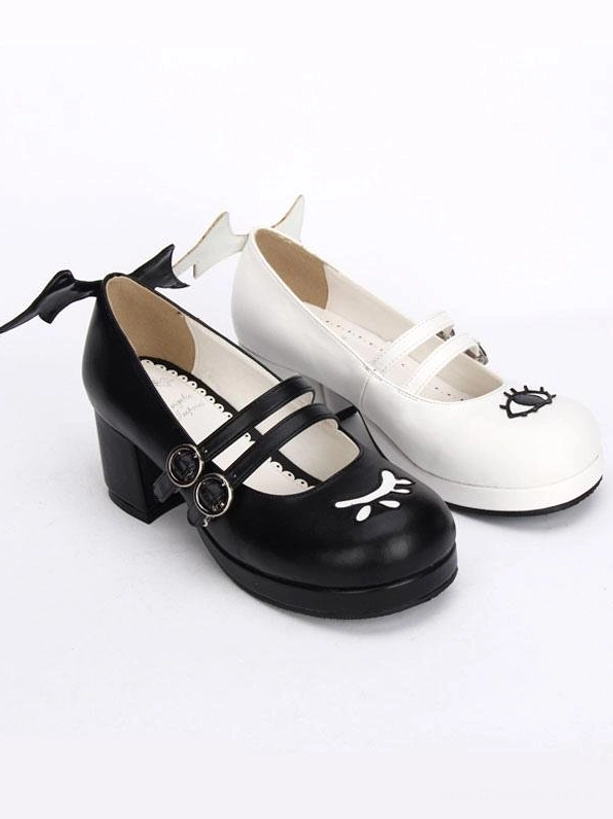 Top down flat lay of double strap Gothic Lolita Mary Jane shoes showing evil wing heel trims dual buckle straps and cute facial prints minimalist background
