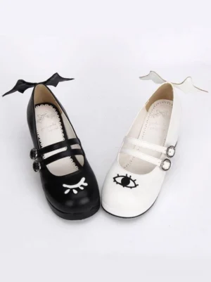 Double strap Gothic Lolita Mary Jane shoes flat lay top view showing evil wing heel trims and cute face prints on vamp in black and white colorway