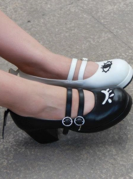 Side top view of worn Lolita Mary Jane shoes with dual buckle straps and evil wing heel details showing facial prints on vamp upper on concrete floor