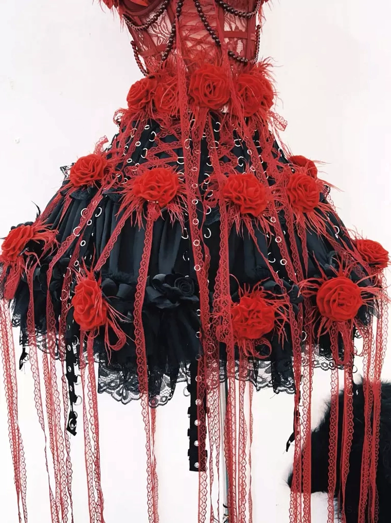 Gothic lolita mini skirt low-angle view featuring ruffled black lace hem with long cascading red tassels and multiple red rose decorations