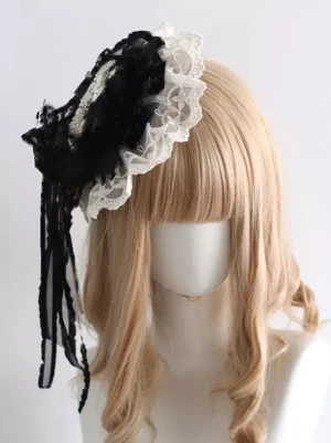 Gothic lolita mini top hat with black and white lace-up construction, featuring white lace frill, black fabric rose ornament, and long sheer ribbon tassels, displayed on mannequin with blonde curly bangs wig - front left view