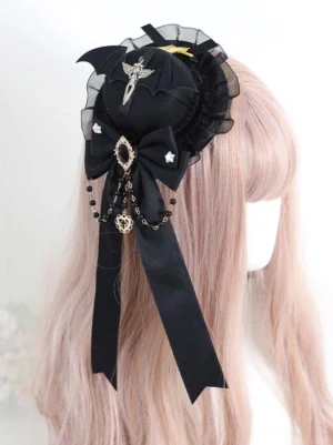 Gothic lolita mini top hat hairclip with black base and ruffled trim featuring black satin bow and bead tassel, shown on pale pink wig mannequin back right three-quarter view