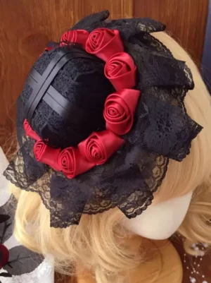 Gothic Lolita mini top hat with wine red satin roses and black lace ruffles worn on blonde mannequin, showing oblique rear view with black satin cross decoration and elegant lace trim detail