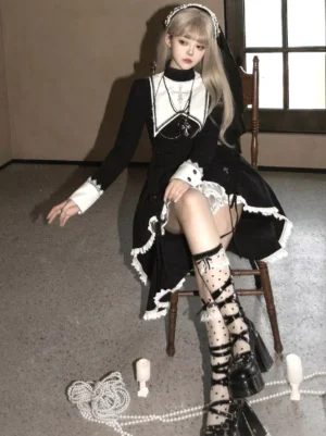 Three-quarter seated view of gothic lolita high-low dress showing ruffled hem details and proportions, styled with white polka dot lace socks and platform lace-up heels on wooden chair