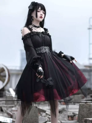 Gothic off-shoulder Lolita OP dress in black and burgundy with ruffled tulle skirt and chain waist belt, front full-body view in abandoned industrial setting