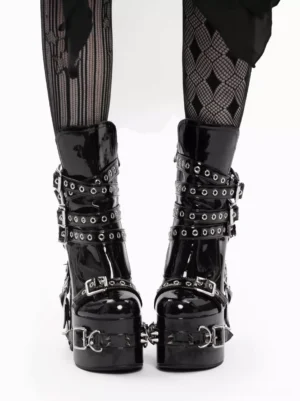 Gothic lolita platform boots direct front view highlighting symmetrical grommet buckle straps, chunky platform heel, and patent leather shine with mesh stockings