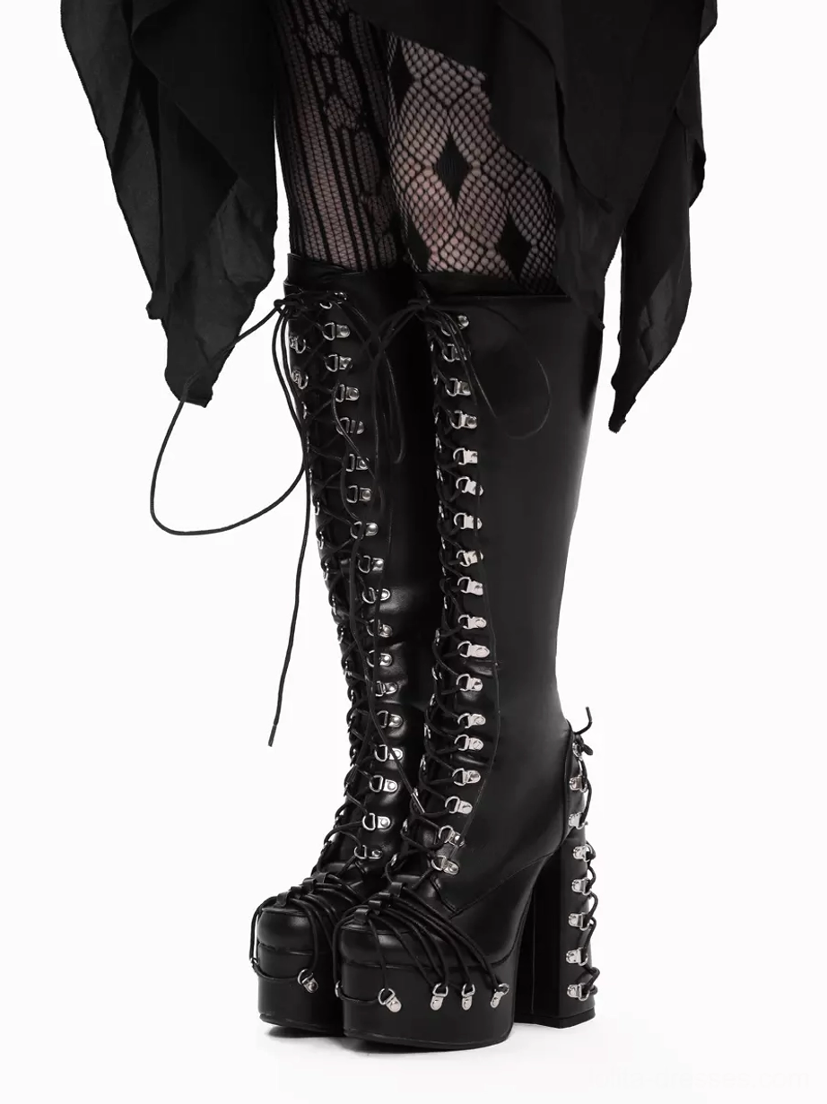 Pair of gothic platform boots front view from slight rear angle, full front lace-up system with silver grommets, prominent platform heels, worn with diamond fishnet tights