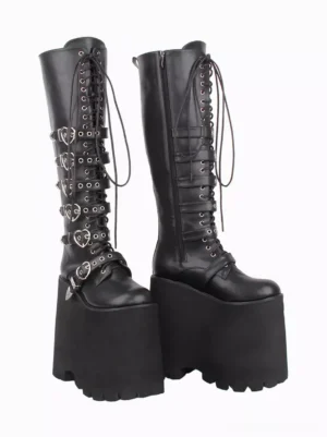 Pair of black Gothic Lolita platform boots featuring chunky lug wedge sole, heart metal buckles, side zipper closure, and lace-up details in front three-quarter perspective