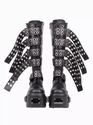 Pair of black punk platform boots with metal buckles and grommet decorated straps overhead front view flat lay on white background showcasing hardware details