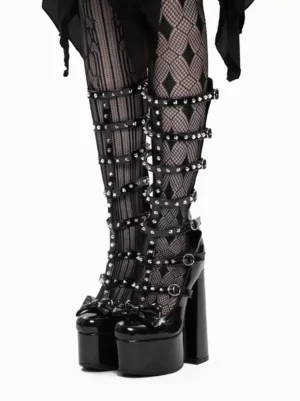 Front close-up of Gothic Lolita tall platform boots featuring glossy patent leather finish, multiple studded buckle straps, bow accent, and thick platform heel with diamond fishnet stockings
