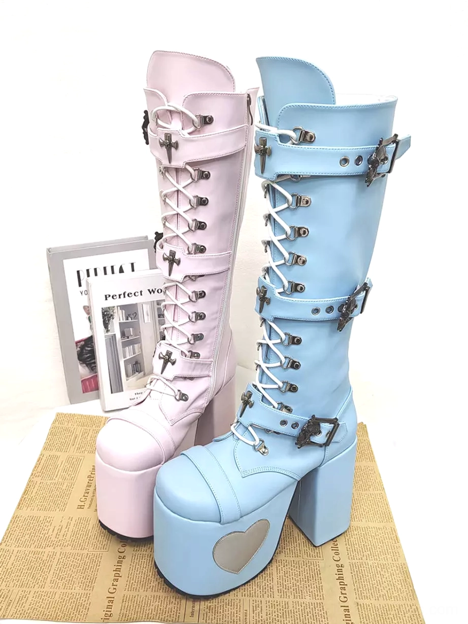 Two pairs of Gothic Lolita platform boots in contrasting colors displayed together featuring cross-shaped metal buckles and dual colorway variants on kraft paper background with magazine prop