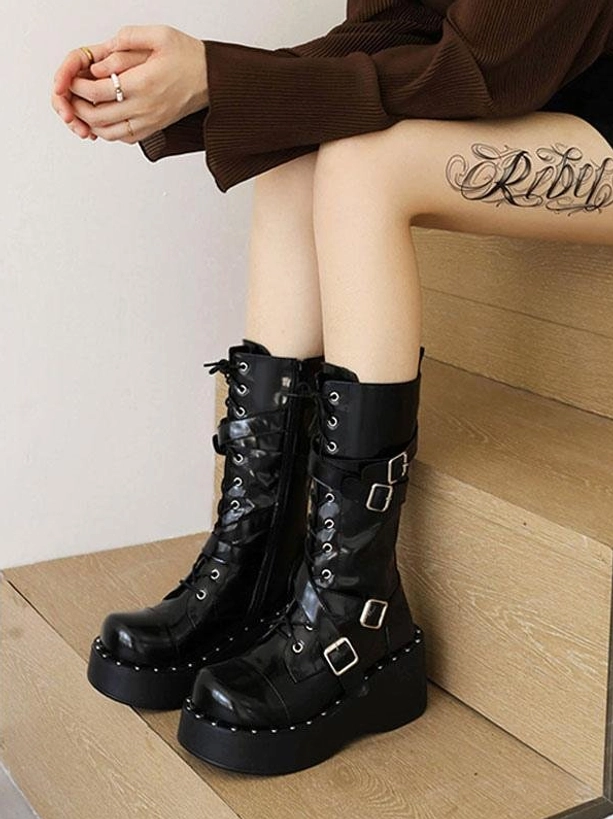 Woman wearing black patent Lolita platform boots on indoor stairs alternate lace-up gothic footwear styling