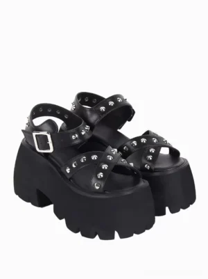 Pair of black Gothic Lolita platform sandals displaying crisscross peep toe straps with pyramid metal details, side three-quarter angle view with adjustable buckle strap and chunky platform sole