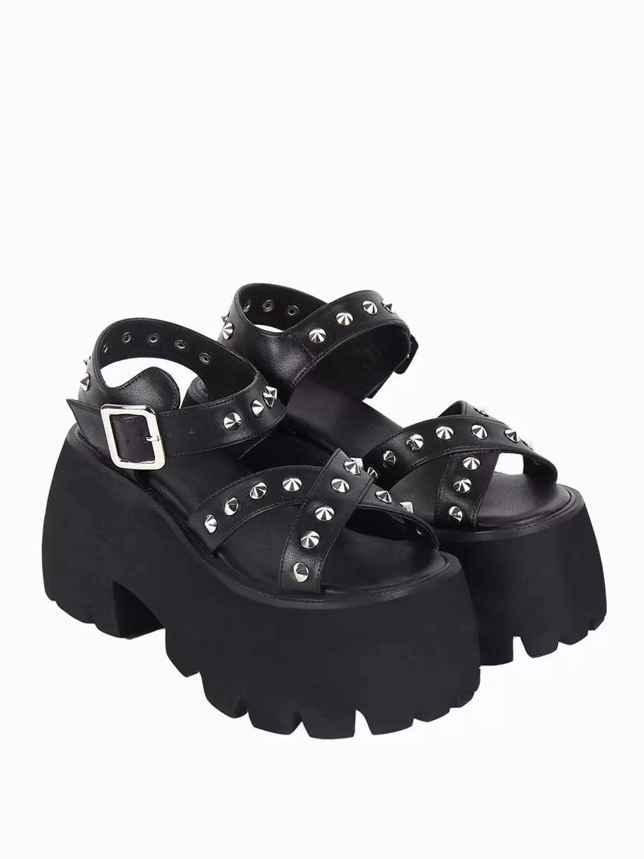 Pair of black Gothic Lolita platform sandals displaying crisscross peep toe straps with pyramid metal details, side three-quarter angle view with adjustable buckle strap and chunky platform sole
