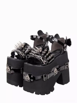 Gothic lolita chunky platform sandals with spike studs and spade skull metal buckles, front three-quarter view, black PU leather open toe design with decorative ankle strap and bow detail