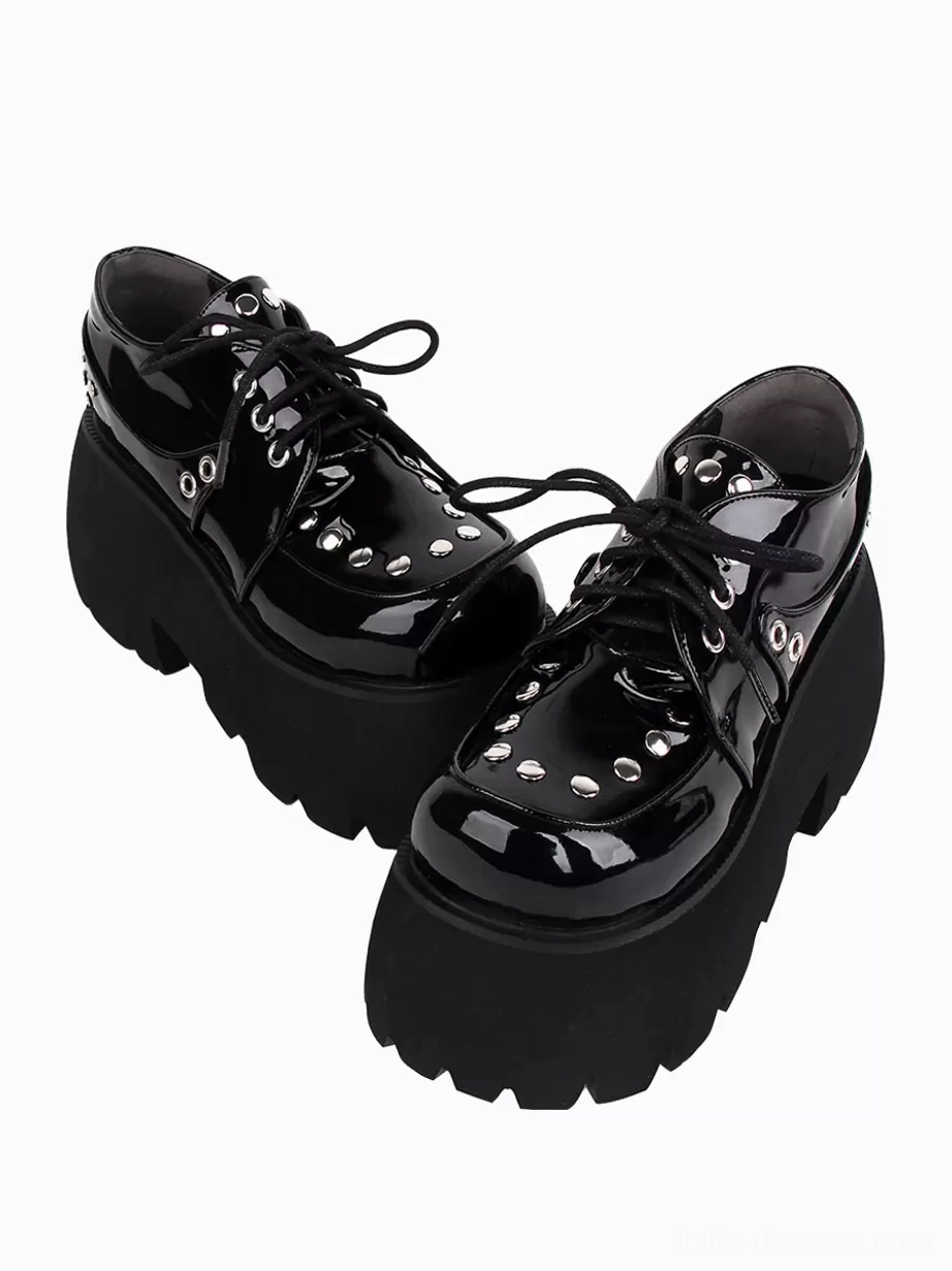 Pair of black Gothic Lolita platform shoes left three-quarter front view showing serrated chunky platform sole and metallic rivet detailing