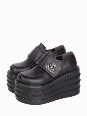 Black gothic lolita platform shoes with skull metal embellishments shown from three-quarter oblique top view, displaying layered wedge sole and hook-and-loop strap closure