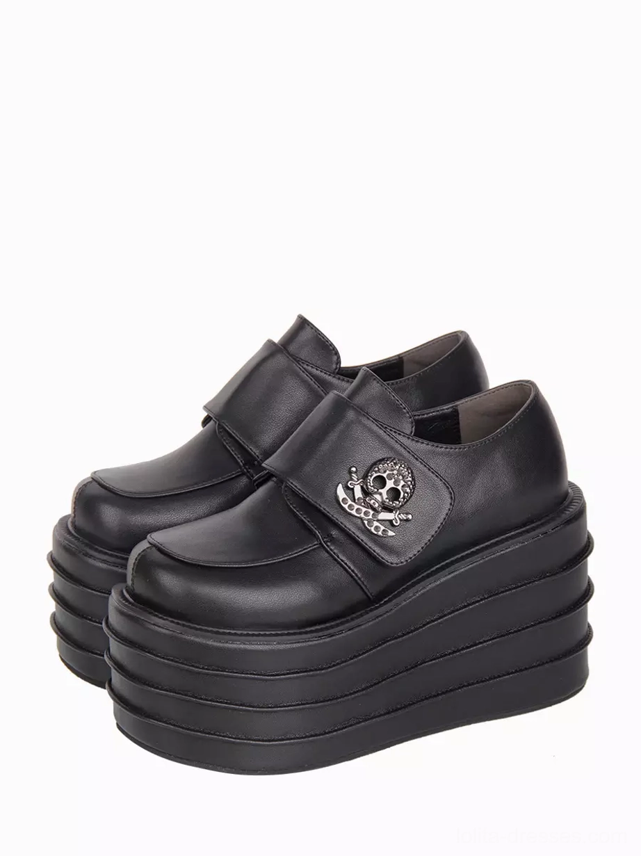 Black gothic lolita platform shoes with skull metal embellishments shown from three-quarter oblique top view, displaying layered wedge sole and hook-and-loop strap closure