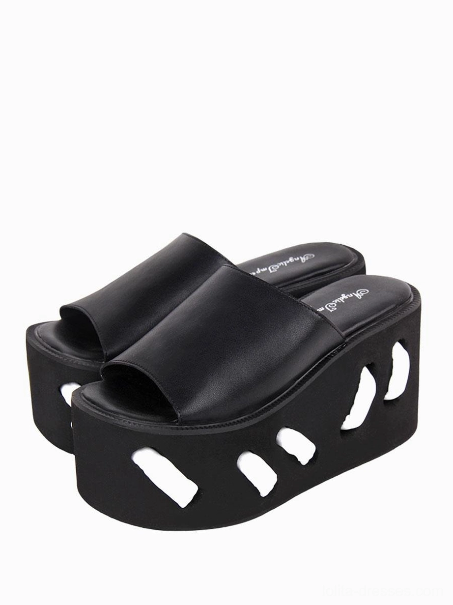 Black gothic lolita platform wedge sandals with geometric cutout pattern front three-quarter view showing matte PU upper and sculptural sole design