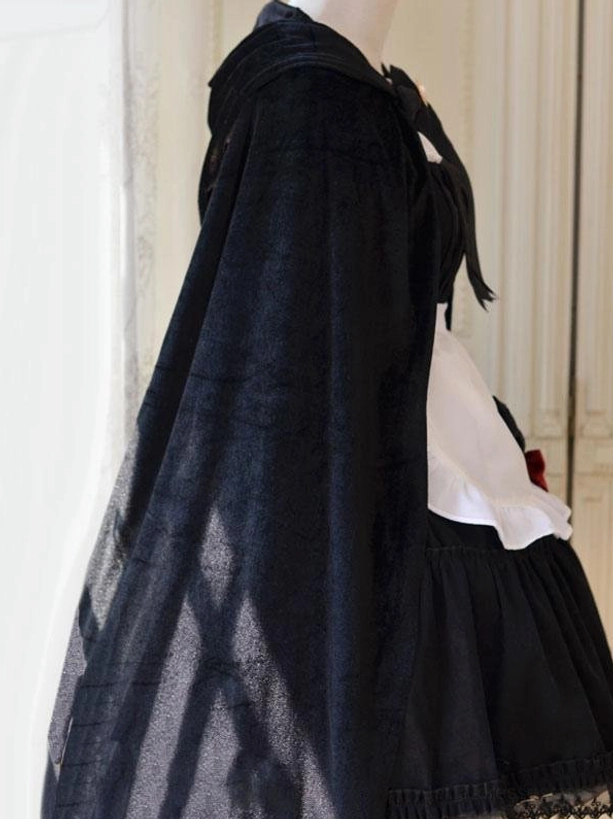 Side profile view of gothic maid lolita suit with black velvet poncho cape, ruffled apron details and black skirt hem