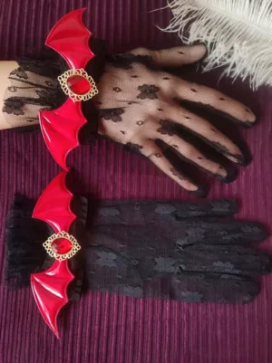 Red variant gothic lolita lace overgloves with sheer floral pattern, iridescent red bat PU trim and red gemstone ornaments, partial wearing demonstration on dark purple ribbed fabric with decorative white feathers