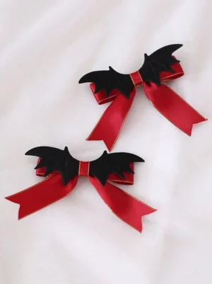 Gothic lolita bat wing bow hair clips red and black two-tone satin design with gold trim and dimensional 3D bat wing faux leather details flat lay