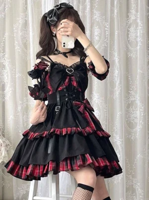 Gothic lolita red plaid jumper skirt low angle seated view showing layered ruffled hem and structured waist corseting