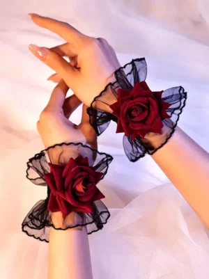 Pair of red rose lace wrist cuffs gothic lolita oversleeves with black mesh ruffles and wine red velvet roses displayed top-down view on white fabric background