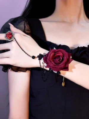 Gothic lolita rose chain hand jewelry worn on upper body front close-up - wine red flocked rose with black lace and metal chains, rose-decorated ring on female model wearing black ruffled lolita dress