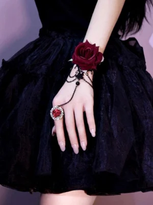 Gothic lolita rose chain hand jewelry side close-up view - layered black chains with wine red rose wrist decoration and connected rose ring on female model in black lolita skirt