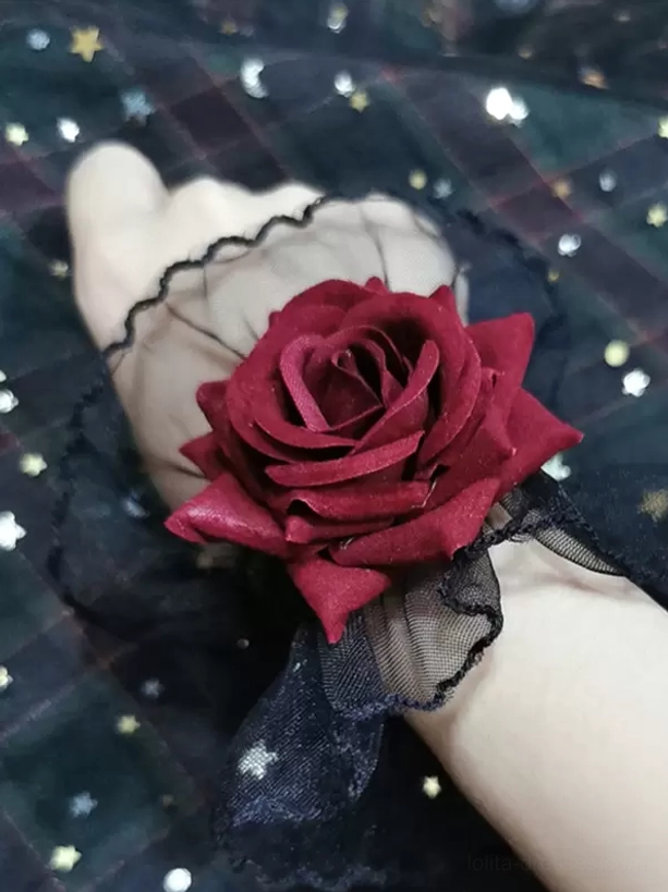 gothic lolita rose wrist cuff close-up showing black sheer mesh ruffle construction and dimensional burgundy fabric rose, side view detail shot against dark star-moon printed background