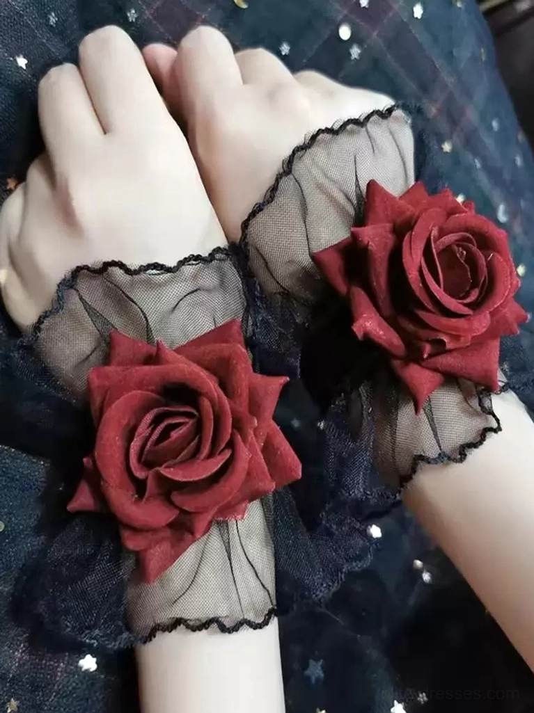 pair of gothic lolita rose wrist cuffs on two hands, top-down view showing matching black sheer mesh ruffles and burgundy roses against dark star-patterned fabric background
