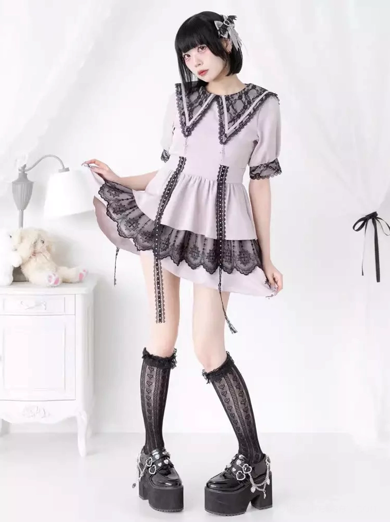 Oblique angle shot of light pink and black lolita dress on model with lifted skirt showing layered ruffles and lace trim sailor collar details