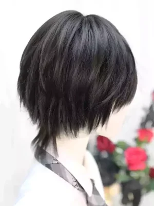 Short black gothic lolita wig with puffy tousled texture and volumetric layers, left rear side view on mannequin wearing plaid tie and white shirt, floral background accent