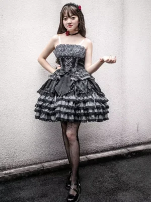 Strapless black and gray Gothic Lolita jumper dress with lace-up corset bodice and tiered ruffle skirt, full front view on model against concrete wall
