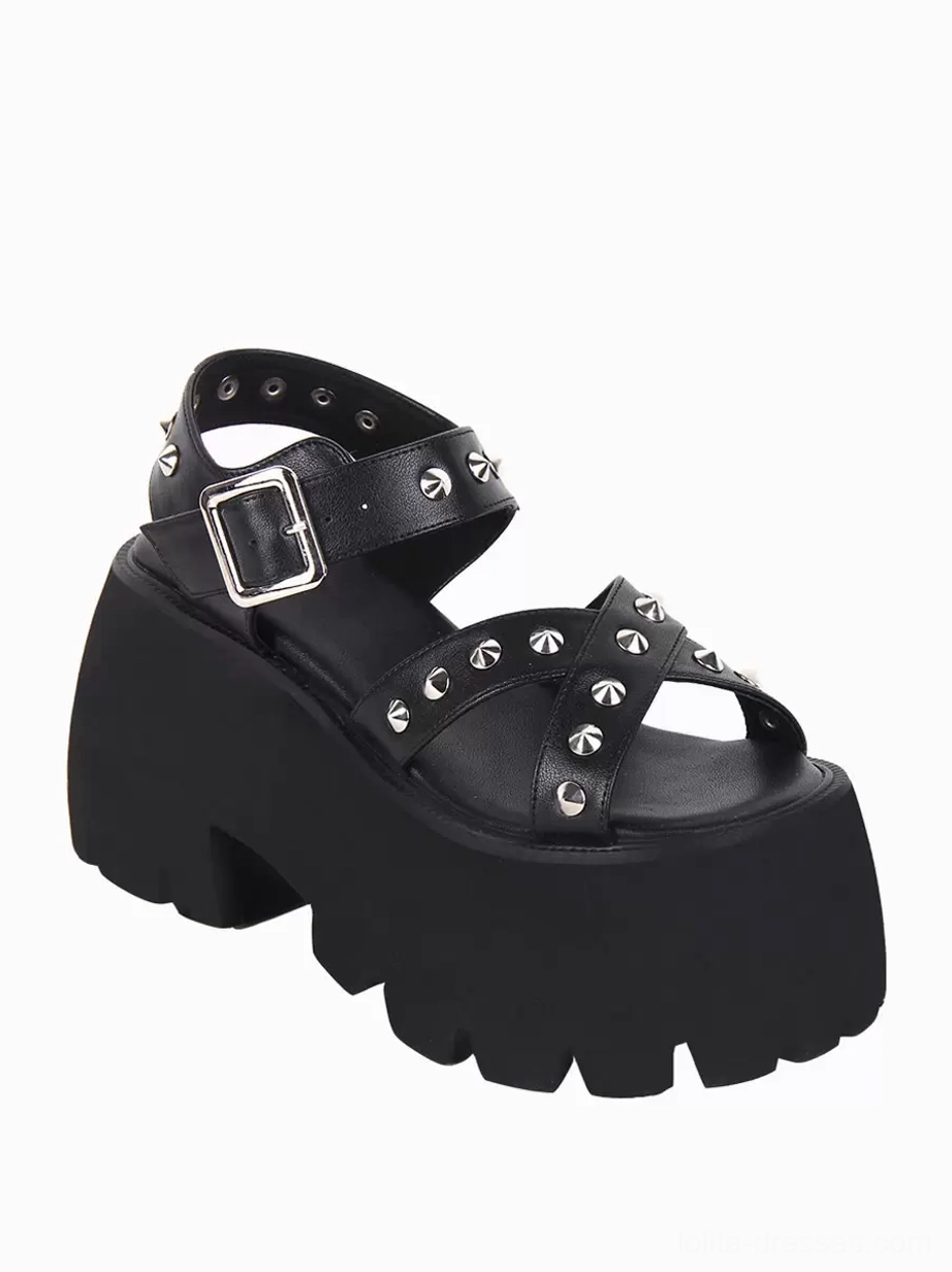 Single black Gothic Lolita platform sandal front side profile showing square metal buckle ankle strap and studded crisscross toe straps with serrated edge platform on white background