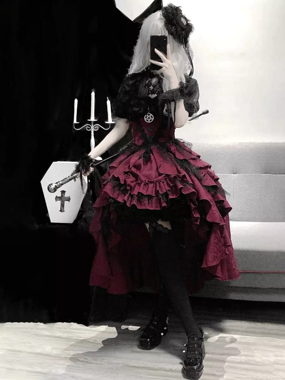 Gothic lolita outfit set full view with mirror reflection showing tiered ruffled skirt, cross-decorated coffin prop, and pentagram top accessory styling on model with dramatic makeup