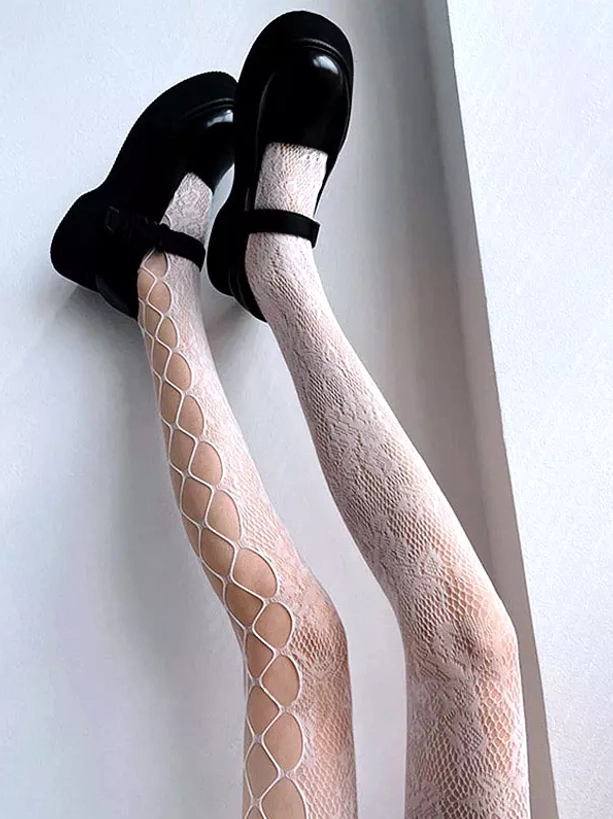 White patchwork fishnet lace stockings overhead view showing white floral lace and beige rhombus hollow mesh design, paired with black platform Mary Jane shoes on gray background