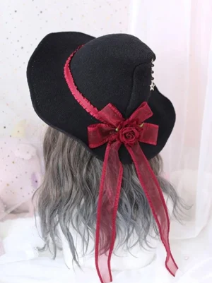 Gothic Lolita witch hat rear top view showing black knitted fabric base with wine red ruffled ribbon and rose bow embellishment with star pendant detail