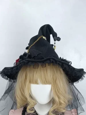 Front view of Gothic Lolita witch hat featuring curved crown, ruffled mesh brim, gold star chain embellishment, and flowing black tulle veil on blonde wig mannequin in pink lolita outfit