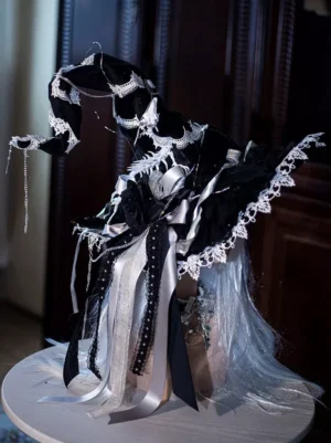 Front three-quarter perspective of gothic wizard headpiece witch hat with curved silhouette, beaded ribbon streamers, and decorative bows displayed on white round stand against dark wood panel background
