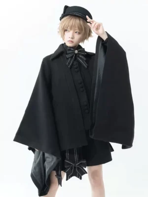 Black Gothic Ouji Lolita cloak front full view with model wearing blonde hair and black newsboy cap, showcasing wide flared sleeves and striped bow tie accent