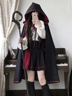 Gothic Ouji Lolita complete outfit set featuring black jacquard cape with high-low hem, long-sleeve bow blouse, and pleated mini skirt with red trim - front mirror selfie view in indoor setting