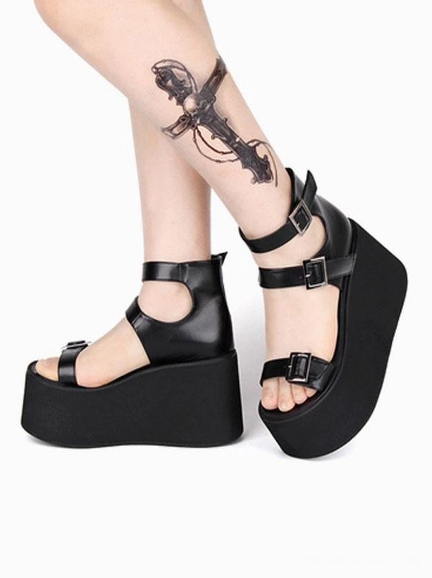 Gothic platform sandals low angle side view showing model leg wearing black shoe with heel back strap, multi-buckle design system, open round toe, matte chunky wedge sole, alternative fashion styling