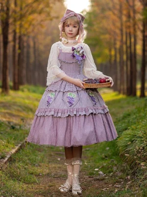 Lavender purple grape print Lolita JSK with flower brooch and multi-layer ruffled skirt - front full-body view held by model with fruit tray