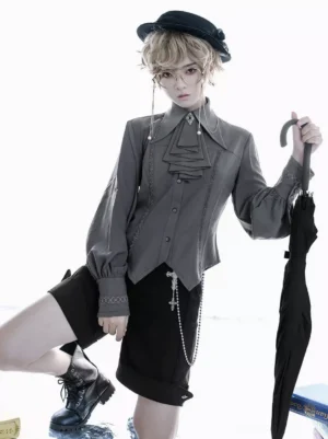 Gray gothic Ouji lolita blouse side view sitting pose showing asymmetric hem and cross chain embellishment detail with formal accessories