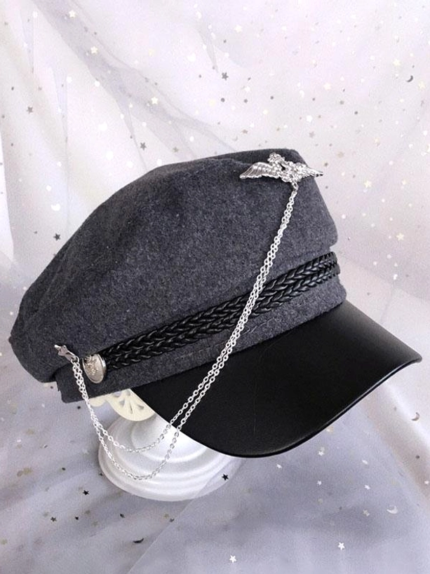 Gray wool lolita military newsboy cap with cascading chain decoration and metal wing brooch, side three-quarter angle displayed on stand with starry tulle backdrop