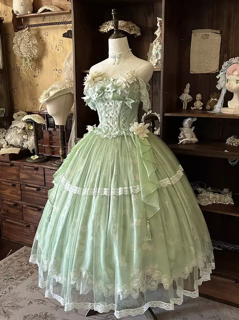Pastoral green floral sweet lolita gown with waist bow accent, lace skirt trim, and floral decorated bodice, antique wooden furniture display scene