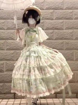 Gothic lolita green dress three-quarter front angle showing flared layered tiered skirt with lace trims, model holding white lace parasol, straw hat accessory